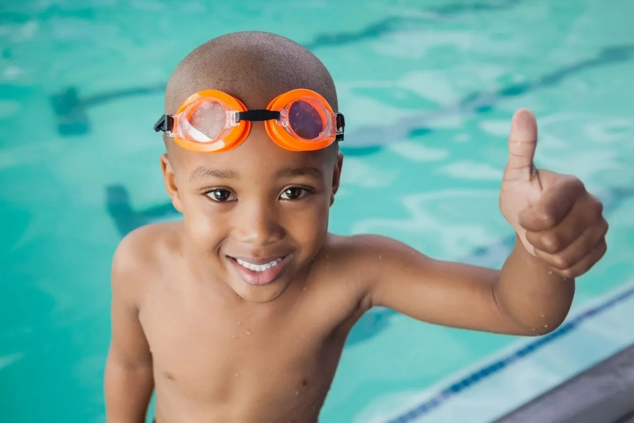 A young boy in the pool wearing goggles